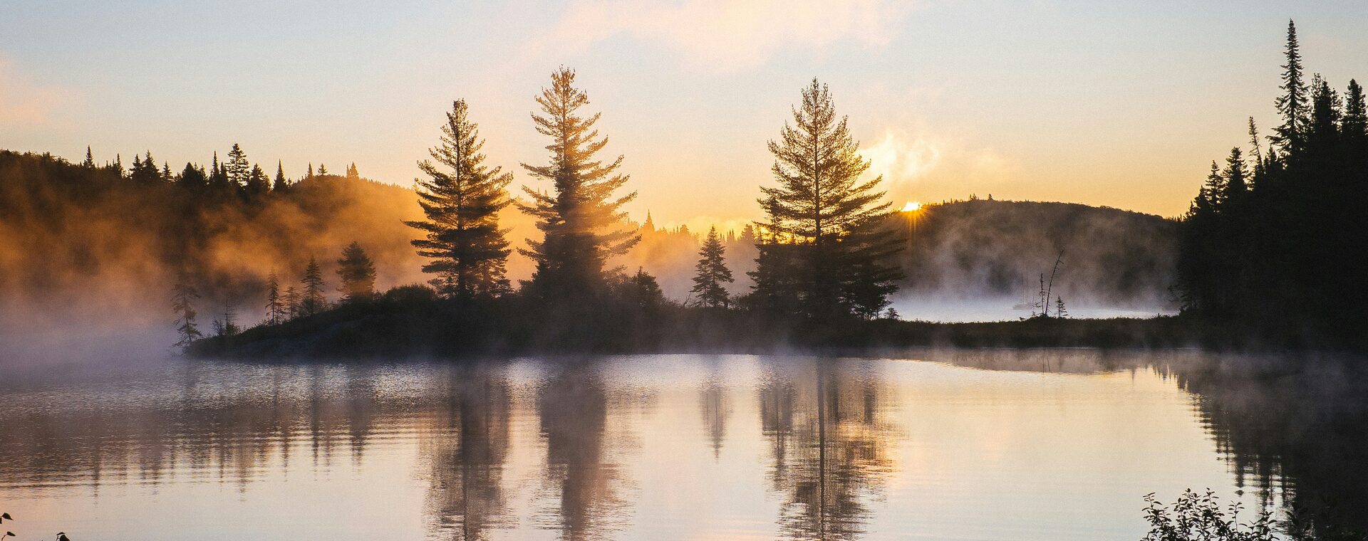 Ruhiger See im Morgennebel bei Sonnenaufgang