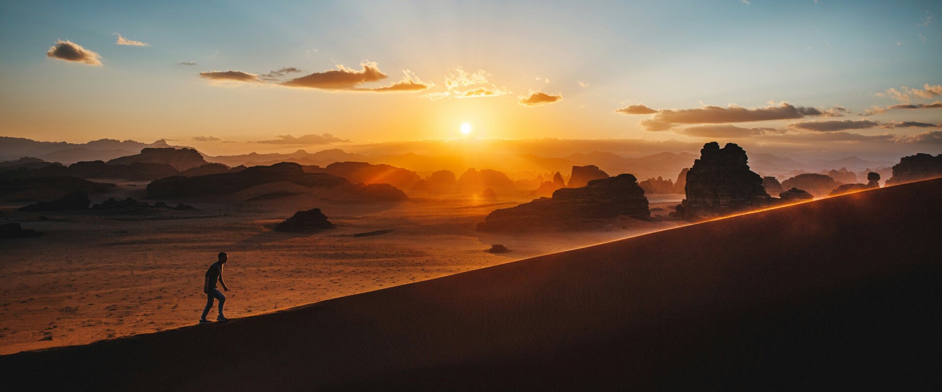 Ein einzelner Läufer in weiter, stiller Landschaft bei Sonnenuntergang